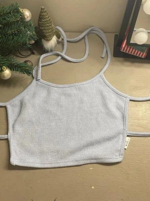 Ljusblå ribbad linnetopp från Gina Tricot - Trendig ljusblå ribbad linnetopp från Gina Tricot med smala axelband och croppad passform. Perfekt för att styla med jeans eller kjol. Mjuk och stretchig känsla tack vare ribbat material.