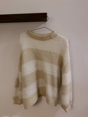 Stickad tröja från LXA - En vit/beige randig stickad tröja från LXA. Väldigt mjuk och mysig att ha på sig! Lite större i modellen. 