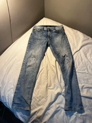 Ljusblå raka replay jeans - Säljer ett par klassiska ljusblå jeans från replay med rak passform och fem fickor. Jeansen har en snygg tvättad look. Perfekta för en avslappnad stil och passar till det mesta. Har ett litet hål men synns knappast. 