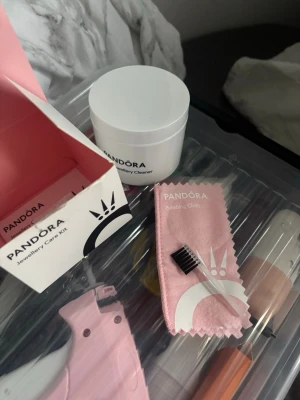 Pandora smyckesvårdskit - Säljer ett Pandora smyckesvårdskit som innehåller en burk Gentle Jewellery Cleaner, en rosa putsduk och en liten borste. Perfekt för att hålla dina smycken rena och blanka. Allt kommer i originalförpackning från Pandora.