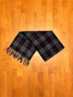 Mörkblå Burberry halsduk - Säljer en mörkblå halsduk från Burberry. Halsduken är i gott skick och är gjord i 100% lamull. Var inte rädd för några frågor. Pris diskuteras inte!