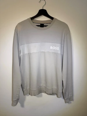 Ljusgrå tröja från BOSS - Säljer en tröja från Hugo Boss. Tröjan är vit/grå. Fin i skicket förutom en missfärgning på axeln som inte märks särskilt mycket. Skriv ett pm för prisförslag eller frågor.
