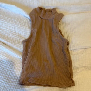 Beige ribbad polotopp från 157 - Säljer en beige ribbad polotopp från 157 i storlek XS/S. Toppen är ärmlös med och har en tight passform. 