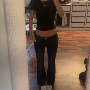 w23 True Religion mörkblå bootcut jeans - pris kan diskuteras. Säljer ett par mörkblå jeans från True Religion med bootcut passform och låg midja. Jeansen har snygga kontrastsömmar, klassiska fickor med lock och vita knappar bak samt logopatch. Materialet är stretchigt jeans och de sitter riktigt snyggt på. knappt användas, w23