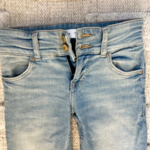 Bootcut jeans med LÅG midja, ljusblå - Snygga ljusblå bootcut jeans med LÅG midja och dubbla knappar fram. Klassisk femficksmodell med slitningar och lätt tvättad look. Jeansen har dragkedja och är tillverkade i jeansmaterial, perfekta för en avslappnad och cool stil. ALDRIG ANVÄNA men GALET SNYGGA