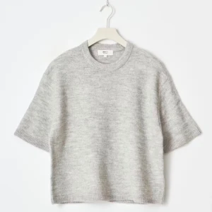 Grå stickad kortärmad tröja - Säljer en ljusgrå stickad tröja från Arket med korta ärmar och rund hals. Tröjan har en loose passform och är gjord i mjuk ullblandning, perfekt för lager på lager under höst och vår. Enkel och stilren design som funkar till allt.