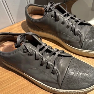 Lanvin dbb1-grey basket basse. Stl 45 - Ett par riktigt fina Lanvin’s som jag köpte i New York 2023. Nypris ~ 5000kr Storlek 45. Det är några märken längst fram vid tårna, några sömmar som gått upp och några få veck här&där.  Spillmärke på skolådan.  2st Dust-bags för skorna. Kvitto finns med.
