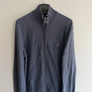 Mörkblå kofta från Polo Ralph Lauren - Snygg mörkblå kofta från Polo Ralph Lauren i mjuk pima bomull. Modellen har hel dragkedja framtill, hög krage och diskret broderad logga på bröstet. Perfekt för lager-på-lager och passar till det mesta. Storlek M, men sitter mer som S.