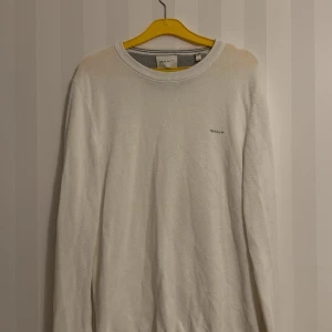 Vit stickad tröja från GANT - Vit stickad tröja från GANT med rund halsringning och diskret logga broderad på bröstet. Enkel och clean design som funkar till många outfits. Inköpt på Thernlunds för ungefär ett år sen. Använd fåtal gånger