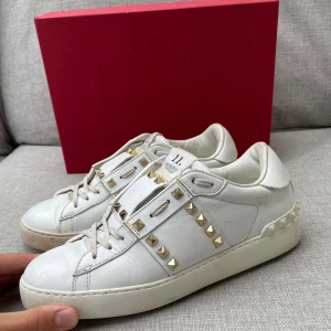 Valentino skor  - Snygga vita Valentino Rockstud sneakers i skinn med ikoniska guldiga nitar längs sidorna! Lite färg på skorna 