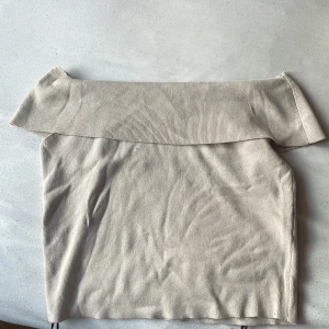 Beige offshoulder topp från H&M - Säljer en beige offshoulder topp från H&M i storlek L. Toppen har en bred krage som vilar snyggt över axlarna och är tillverkad i mjuk, ribbad bomull. Perfekt för dig som gillar stilrena och enkla plagg med en modern touch.