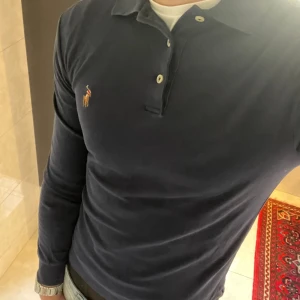 Pikétröja från Polo Ralph Lauren - Säljer en stilren marinblå långärmad pikétröja från Polo Ralph Lauren i slim fit, XS. Inga defekter, som ny. Jag är 179 på bilden och den sitter litet. Nypris: 1400. Mitt pris: 299