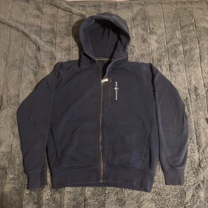 Sail Racing Hoodie (PRIS KAN DISKUTERAS!) - Snygg marinblå hoodie från Sail Racing med dragkedja framtill och bröstficka med logga. Tröjan har huva, långa ärmar och ribbade muddar. (Pris kan diskuteras)
