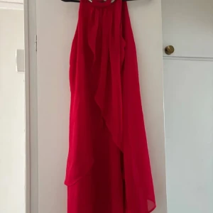 Röd klänning med glittrig hals - Säljer en röd klänning med halterneck och glittrig dekoration runt halsen. 