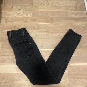 Svarta Replay Anbass jeans  - Svarta Replay Anbass jeans med slim passform och klassisk femficksdesign. Jeansen har en snygg mörk tvätt, diskret Replay-logga på bakfickan och svart läderpatch i midjan. Perfekta för dig som gillar en tight och stilren look. Strl W28 L32