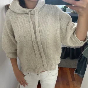 Beige stickad hoodie med huva - Trendig & Mysig beige stickad hoodie med huva och snörning. Tröjan har ribbade muddar och en avslappnad passform med trekvartsärmar. Storlek xs men passar S mer. Perfekt för hösten💕