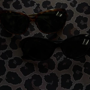 Två par solglasögon H&M & 9&CI - Säljer två par snygga solglasögon! Ett par är svarta med cat eye-form från H&M, och det andra paret är bruna med sköldpaddsmönster och guldiga detaljer från 9&CI. Perfekta accessoarer för att lyfta din stil.