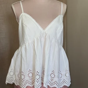 Vit broderad linnetopp BW Dream catcher - Superfin vit linnetopp med smala axelband och v-ringning. Toppen har broderade hålmönster längs fållen samt volangig, luftig passform. Perfekt för varma dagar och sommarvibbar. Originalpris 399kr men jag säljer för 70kr. Helt ny från bik bok. Justerbara axelband. 