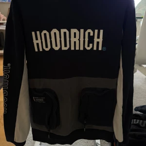 Svart och grå hoodie från Hoodrich - Säljer en svart och grå hoodie från Hoodrich med stor logga på bröstet och ryggen. Tröjan har två praktiska fickor med dragkedja framtill, kontrastfärgade ärmar och en grå huva. Skick 9/10, de finns inga fläckar eller hål osv. Om du har fler frågor eller är intresserad, skriv privat