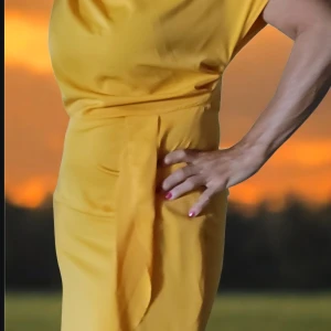 Gul omlottklänning - Snygg gul klänning med omlottkänsla. Modellen är figurnära och har en stilren, enkel design utan ärmar. Perfekt för dig som vill sticka ut med en färgstark look.