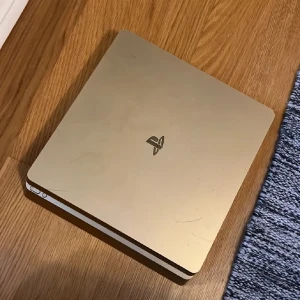 PlayStation 4 Slim Gold Edition - Snygg PlayStation 4 Slim Gold Edition. Konsolen har synliga repor och slitage på både ovansida och undersida, men är i fullt fungerande skick. Perfekt för dig som vill ha en unik PS4 till ett bra pris. Alla portar ser hela ut.