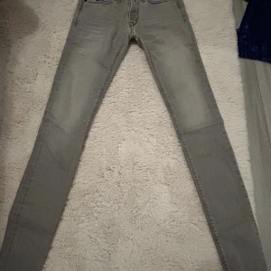 Grå Replay skinny jeans - Säljer ett par grå skinny jeans från Replay med klassisk femficksdesign och snygga detaljer på bakfickorna. Jeansen har en smal passform och är tillverkade i stretchigt jeanstyg för extra komfort. Perfekta för dig som gillar en stilren och modern look.