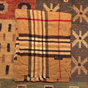 Vintage Burberry halsduk  - -Riktigt bra skick. Nypris på dessa ligger på runt 5000kr, vilket gör detta till ett sjukt bra pris! Halsduken är gjord i Lamull, och är perfekt inför hösten och den kommande vintern. Anledningen till att det står ”Burberry’s” och inte ”Burberry” på lappen är eftersom halsduken är från några år tillbaka, innan de bytte namn! Om du har någon fråga är det bara att skriva till mig. /elgnce (5)