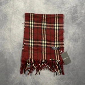 Burberry Halsduk - Skick: 7/10 (Vintage), begagnad, inga defekter. | Vad som ingår: Endast halsduken. | Ordinarie pris: +- 4000 SEK / 400 €. | ​​OBS: Halsdukarna finns i samma färgsättning men kan skilja sig något i modell eller detaljer, beroende på tillverkningsår eller kollektion