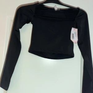 Svart långärmad topp från Nelly XS - Säljer en svart långärmad topp från Nelly i modellen Flirty Square Top. Toppen har en fyrkantig halsringning och är croppad i stilen. Materialet är mjukt och stretchigt, perfekt för att skapa en clean och snygg look. Passar dig som gillar minimalistisk stil.