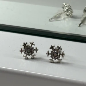 Silvriga snöflingeörhängen  - Supersöta örhängen i form av snöflingor i silverfärg med små glittrande stenar i mitten. Aldrig använda!