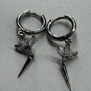 Silvriga örhängen med kristallblad - Säljer ett par coola silvriga örhängen med små gnistrande kristaller formade som blad och en spetsig hängande detalj. Använda några gånger!