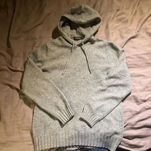 Grå hoodie från Dressmann i ullmix - Mjuk och skön grå hoodie från Dressmann i storlek M. Tröjan har huva med snörning, ribbade muddar och är tillverkad i en blandning av 50% bomull och 50% ull. Perfekt för kyliga dagar och har en klassisk, enkel look som funkar till jeans eller mjukis.