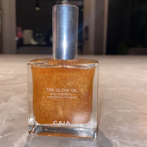 CAIA The Glow Oil shimmerolja - The Glow Oil från CAIA är en skimrande kroppsolja med guldigt skimmer, berikad med avokadoolja och vitamin E. Kommer i en snygg fyrkantig glasflaska med silvrig kork. Perfekt för att ge huden en glowy finish.