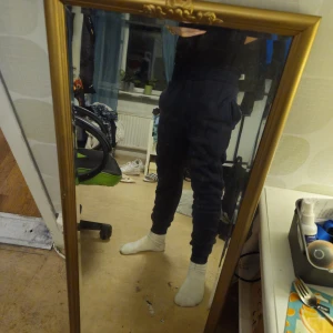 Mörkblå mjukisbyxor från Polo Ralph Lauren - Mörkblå mjukisbyxor från Polo Ralph Lauren med röd broderad logga på höften. Byxorna har dragsko i midjan och är tillverkade i mjukt bomullsmaterial. Perfekta för chill dagar eller när du vill vara bekväm men ändå se snygg ut.