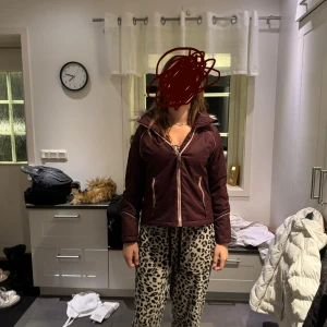 Vinröd vinterjacka med fuskpäls - Säljer en vinröd vinterjacka från Didriksons med mysig fuskpäls på luvan. Jackan har dragkedja framtill, två fickor med dragkedja och snygga ljusa detaljer längs sömmarna. Perfekt för kalla dagar och riktigt skön passform.