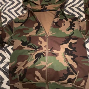 Camouflage hoodie från Polo Ralph Lauren - Säljer en hoodie från Polo Ralph Lauren i camouflage-mönster med dragkedja och huva. Tröjan har känguruficka framtill och är i mjuk bomullsmix. Perfekt nu till vintern väldigt varm och skön behaglig att bära på också spelar inte roll om de är i skolan,jobbet eller bara chill kväll hemma. Kom med frågor och funderingar ❤️🤙