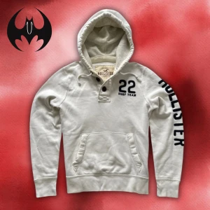 Vit hoodie från Hollister - Vit hoodie från Hollister med svart tryck på ärmen och bröstet, väldigt lite fläckar som inte syns | Size M | Längd: 68cm Axelbredd: 60cm Armlängd: 68cm | Passar för 175-190