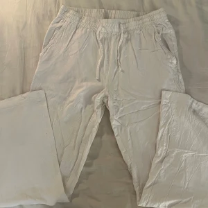 Vita linnebyxor med snörning - Snygga vita linnebyxor med elastisk midja och snörning framtill. Byxorna har raka ben, sidofickor och en bakficka. Perfekta för chill dagar och har en skön loose passform. Lätta och luftiga i materialet. Vet varken märke eller storlek men jag har s och är 172cm och det är lite korta men annars bra. 