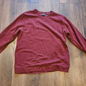 Vinröd sweatshirt från Dressmann - En enkel och stilren vinröd sweatshirt från Dressmann i storlek L. Tröjan har rund hals och långa ärmar, tillverkad i mjuk bomull som är skön att bära. Perfekt för dig som gillar klassisk och avslappnad stil.