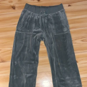Gråa velourbyxor Juicy Couture XS - Mysiga gråa mjukisbyxor från Juicy Couture ,med bred resår och snörning i midjan. Byxorna har stora fickor fram och bak, samt broderad JC-logga på ena fickan. Liten fläck på knät och liten lim fläck på låret men inget som syns jättetydligt. De är i xs men passar S också (jag använder själv S för det mesta och de passade bra på mig) kontakta mig ifall man vill ha mer bilder på byxorna, om man är intresserad eller frågor💞 