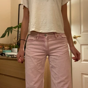 Ljusrosa baggy jeans - Säljer ett par ljusrosa jeans med baggy passform och klassiska fem fickor. Jeansen är mid waist och är tillverkade i mjukt bomullsmaterial. Perfekt för dig som vill sticka ut med färg och samtidigt ha en skön och avslappnad stil. Perfekta vår byxor!