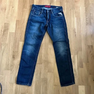 Replay Jeans Anbass - Snygga Replay Anbass jeans i klassisk blå tvätt med coola slitningar och raka ben. Jeansen har tydliga sömmar och en bekväm midja. Perfekta för dig som gillar stilrena och tidlösa jeans.