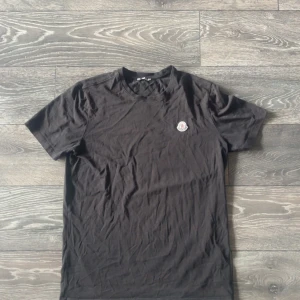 Moncler tisha  - En moncler tisha köpt här på Plick har använts den kanske 2 gånger sen glömde jag bort den typ men de e inga defekter på den eller något. 