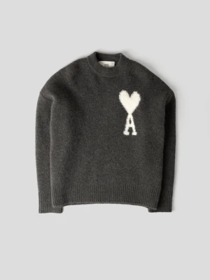 Mörkgrå stickad tröja från Ami - Säljer en mörkgrå stickad tröja från Ami med en vit hjärtformad detalj och bokstaven A på bröstet. Tröjan har rund hals och långa ärmar med ribbade muddar. Perfekt för dig som gillar stilrena och coola plagg med unik design.