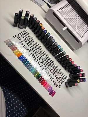 Färgglada nagellack i olika nyanser - Säljer ett stort set med nagellack i många olika färger, allt från nude och pastell till starka blå, gröna, röda och rosa nyanser. Flaskorna är svarta med färgkod på locket och passar perfekt för dig som gillar att variera din nagelstil. Perfekt för kreativa nageldesigner!