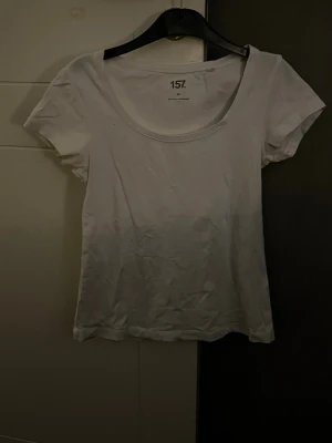 Vit t-shirt från 157. - En enkel vit t-shirt från 157. med rund hals och korta ärmar. Modellen är klassisk och passar perfekt till jeans eller shorts. Tillverkad i mjuk bomull som känns skön mot huden. Perfekt för dig som gillar en clean och basic stil.