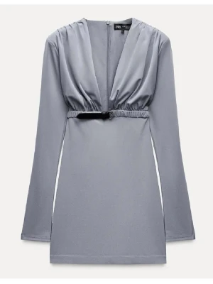 Grå kortklänning från Zara - Snygg grå kortklänning från Zara med djup v-ringning och långärmad design. Klänningen har ett coolt bälte i midjan och är tillverkad i ett mjukt syntetmaterial. Perfekt för dig som gillar stilrena och moderna plagg. oanvänd med lapp kvar.