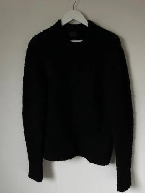 Svart stickad tröja Studio Zara Man - Svart stickad tröja från Studio Zara Man, tillverkad av italienskt garn. Tröjan har en enkel, klassisk design med rund hals och långa ärmar. Materialmixen består av akryl, ull, polyamid, alpacka och elastan vilket gör den mjuk och lite fluffig. Perfekt för dig som gillar stilrena och bekväma plagg. 6P3