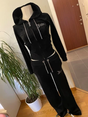 Lyxig Juicy Couture Set - Snyggt svart Juicy Couture-set med zip-hoodie och matchande byxor. Detaljer i strass på dragkedjor, snören och logga, vilket ger en lyxig och trendig look. Köpt för 3600 kr🖤