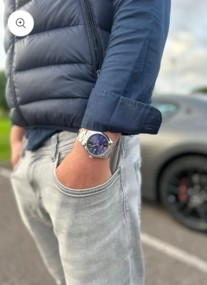 Blå klockan från Doventi  - Stilren herrklocka från Doventi med blå urtavla och silverfärgat armband i metall. Klockan har datumvisning och klassisk rund form med tydliga indexmarkeringar. Perfekt accessoar för dig som gillar en clean och modern look.